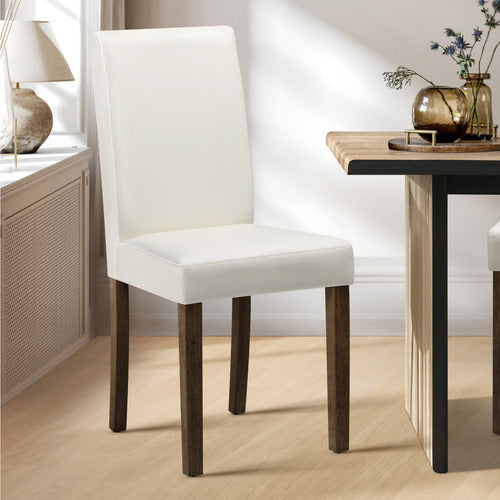 White chair with wooden legs in a room with a table and decorative items.